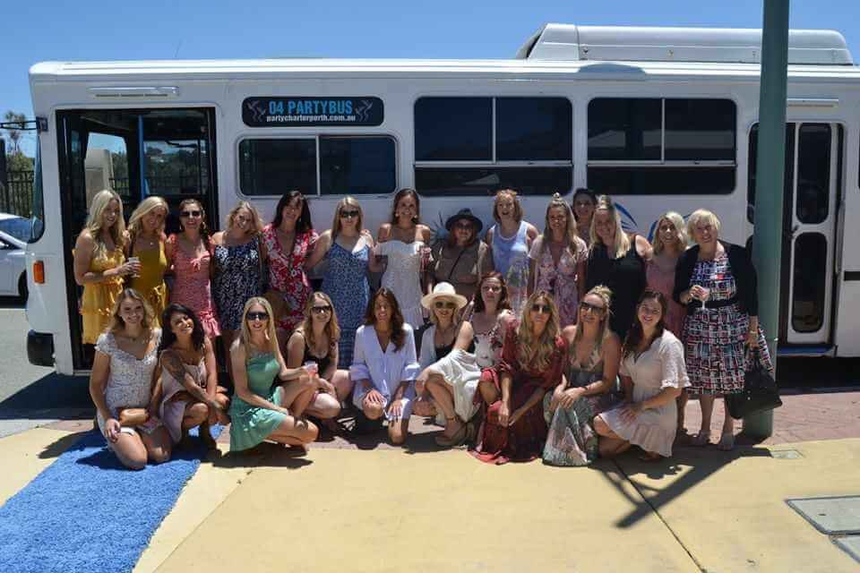 A group of women posing in front of a party bus during a hen party.