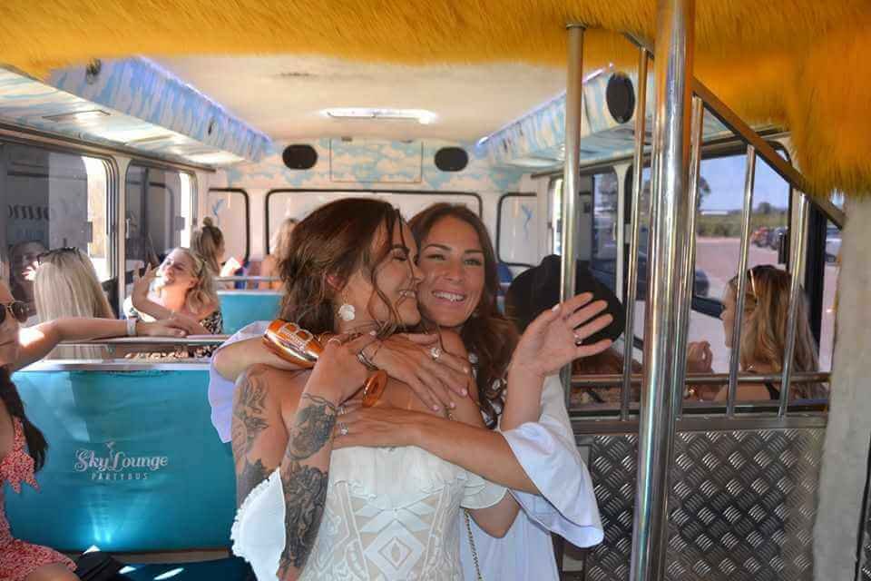 Two women laughing inside a party bus during a hen party.