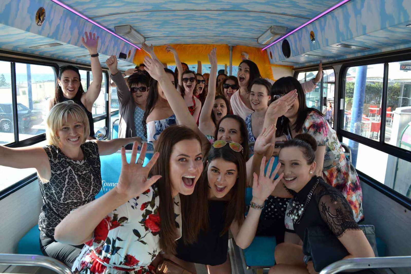 A group of cheerful women pose inside a party bus ready to go on their wine tour.